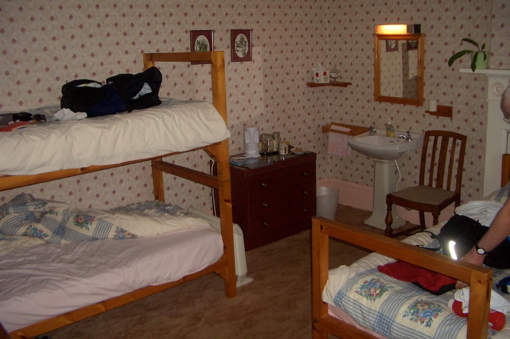 Dated bedroom with bunkbeds and sink in corner.