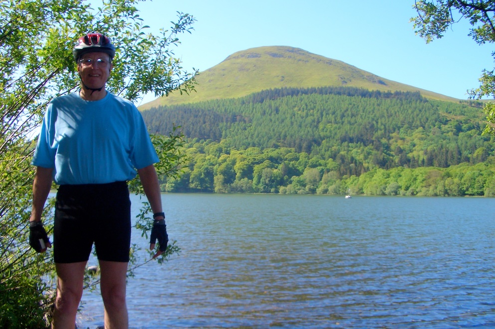 Peter on shore of lake with hill in background