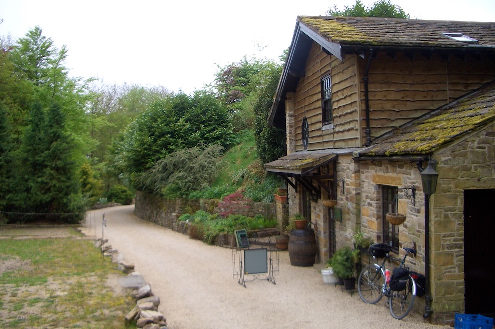 old forge building with gravel driveway; bike parked outside.