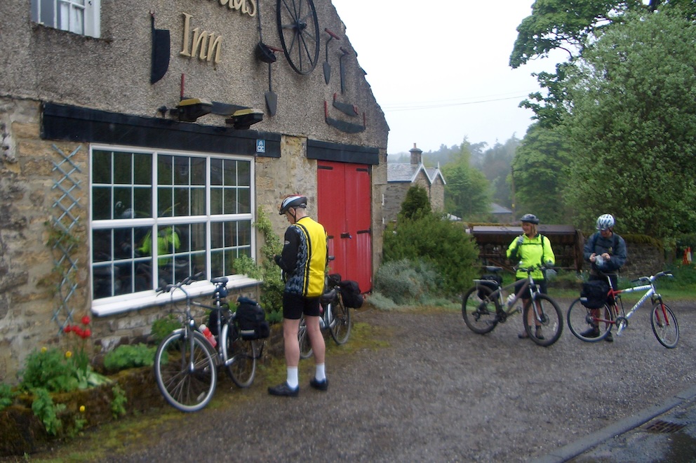 Peter and Sue and John outside inn with bikes.