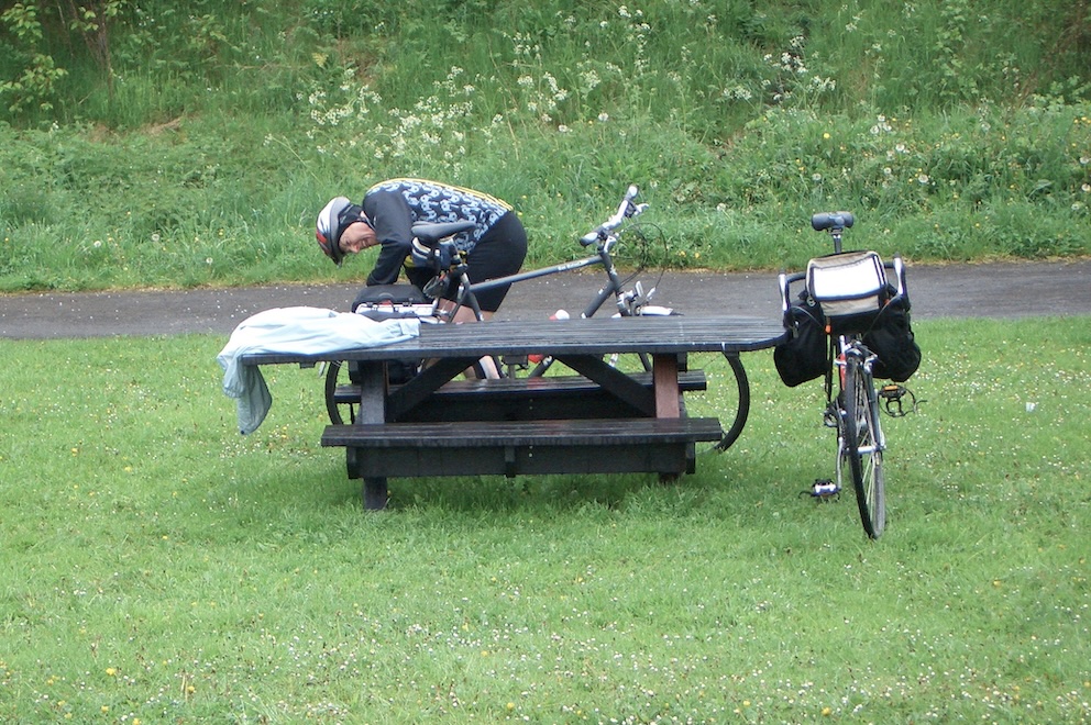 Peter getting gear from bike propped against picnic table.