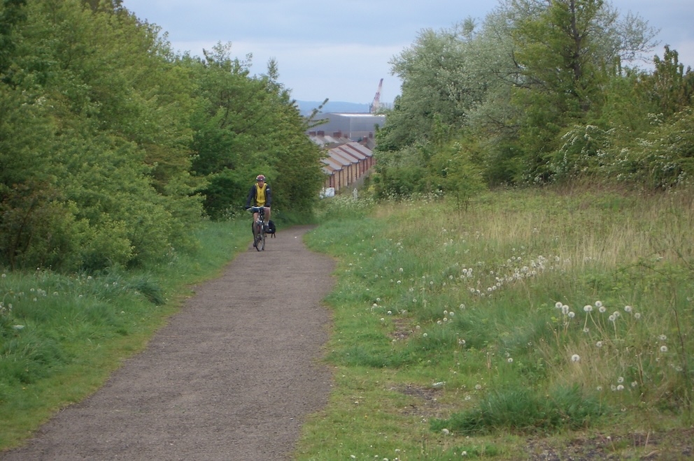 Peter on gravel path flanked by small trees.